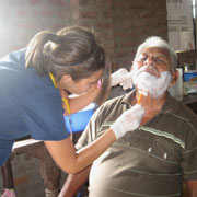 Nursing student shaving older man.